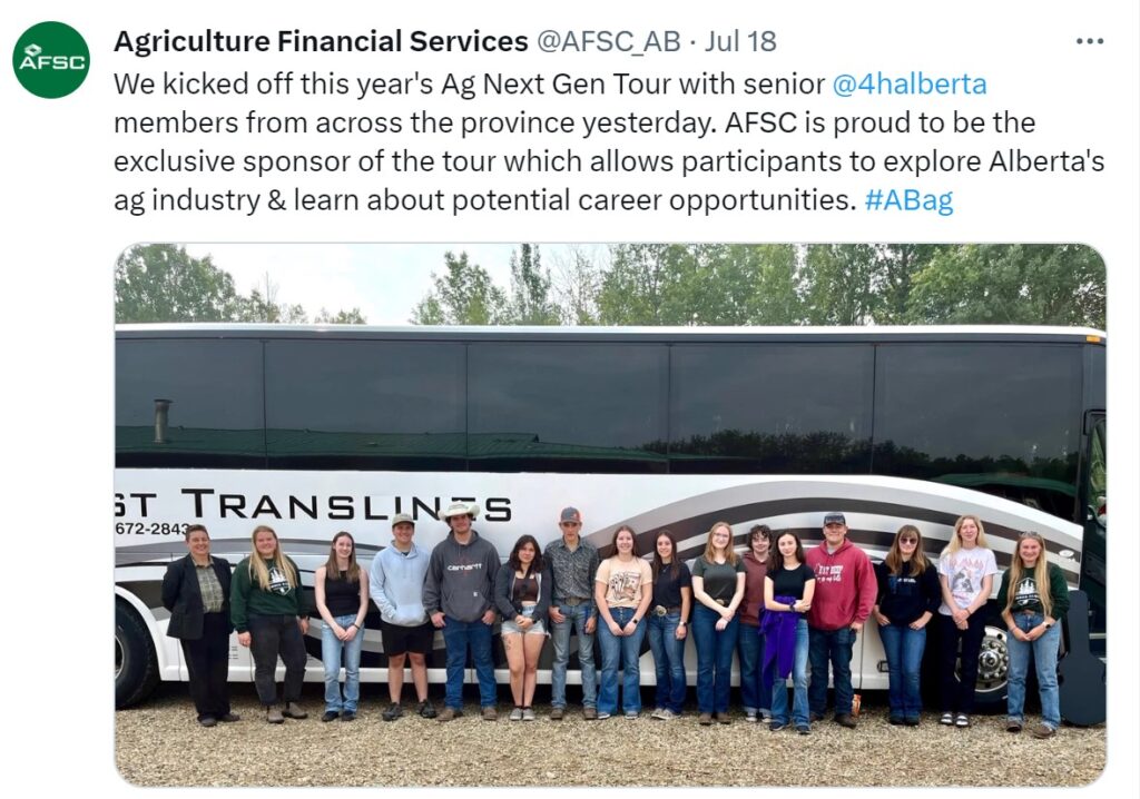A group of senior 4-H members stand in front of a bus.