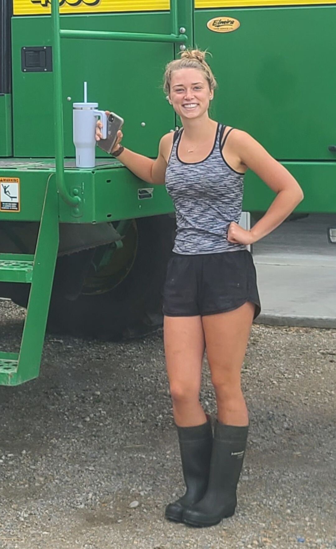 A person wearing boots, standing in front of a tractor.