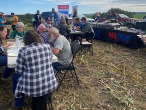 A picture of a group of people enjoying a meal in the field.