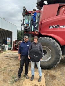 A family poses in front of a combine with a prize from AFSC.