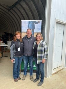 Three people pose for a photo in front of an Agriculture Financial Services banner.