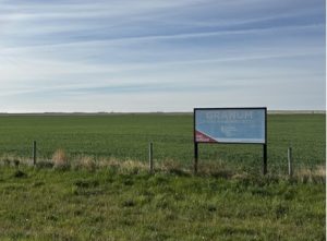 Picture of a field with a Granum Foodgrains Growing Project sign in the foreground.