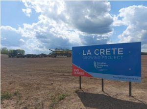 Picture of a field with a La Crete Foodgrains Growing Project sign in the foreground.