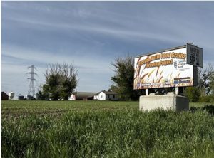 Picture of a field with a Picture Butte Foodgrains Growing Project sign in the foreground.