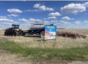 Picture of a field with a Westfield Foodgrains Growing Project sign in the foreground.