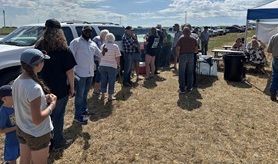 A group of people gather to eat lunch in a field.