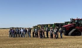 A group of people standing in front of a row of tractors.