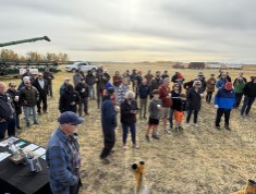 A group of people stand in a harvested field.