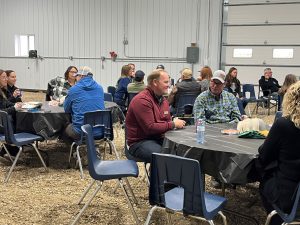 People seated at tables inside a quonset chat with one another.
