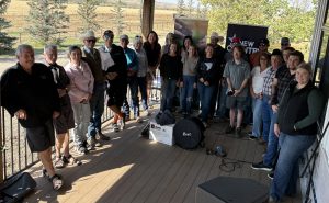 A group of people on a covered deck pose for a photo.