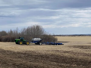 A green tractor pulls an air seeder