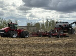 A red tractor pulls an air seeder.