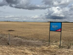 A stubble field with a Canadian Foodgrains Bank sign