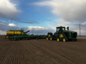 A green tractor pulls an air seeder