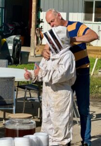A person secures a protective bee hat onto a youth's head.