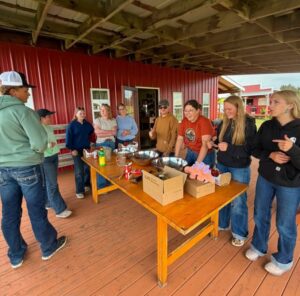 A group of youth stand around a table that has canning supplies on it.