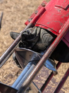 A workboot entangled in a red grain auger.