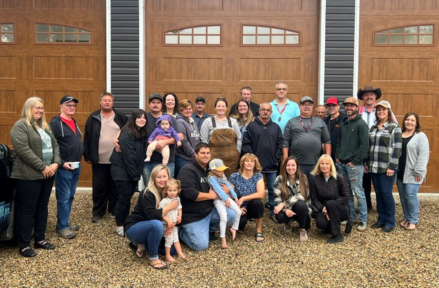 A group of people gathered in front of a garage door for a photo