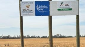 Canadian Foodgrains and AFSC signage stand in front of a crop that's almost ready to harvest